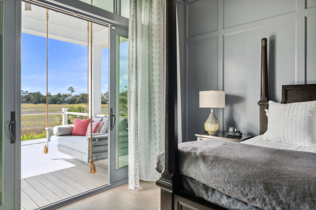 bedroom with a bed and lamp overlooking porch with porch swing on the water