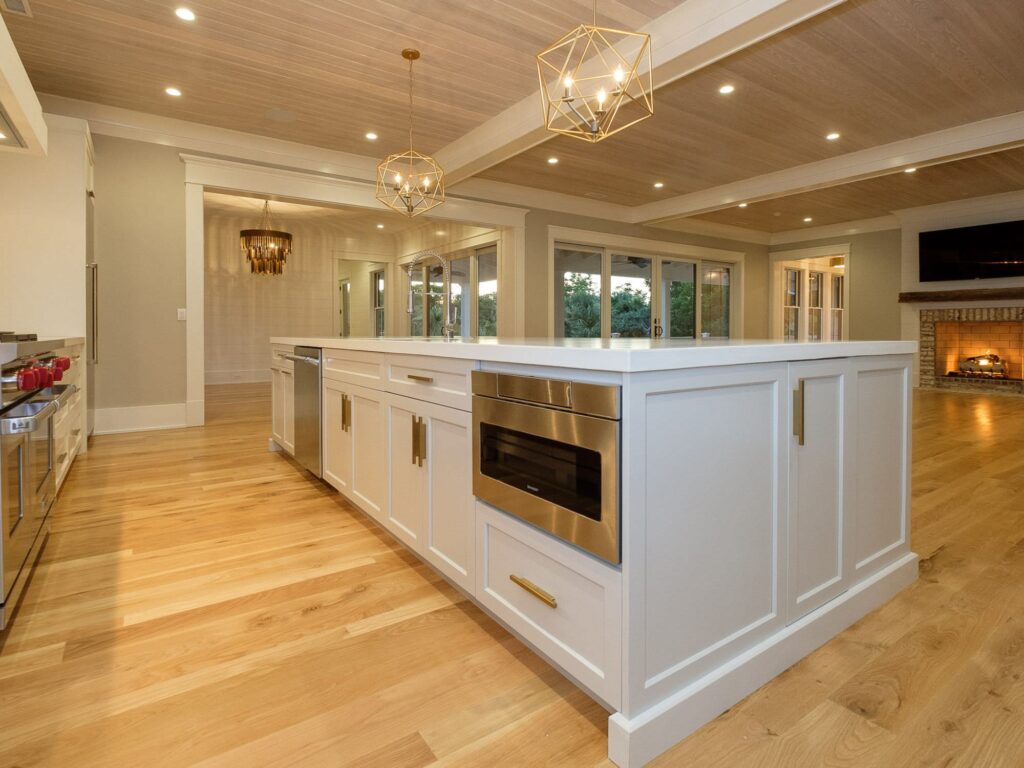 huge kitchen with new floors and island with modern lights hung above