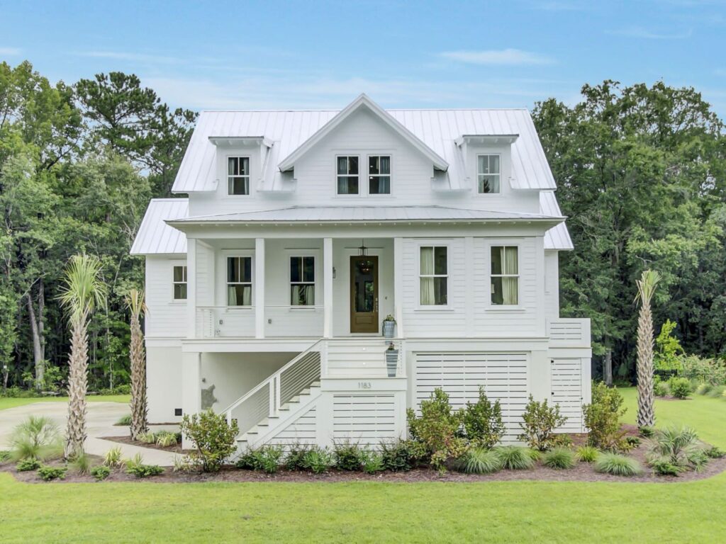 two story white home with palm trees and green grass